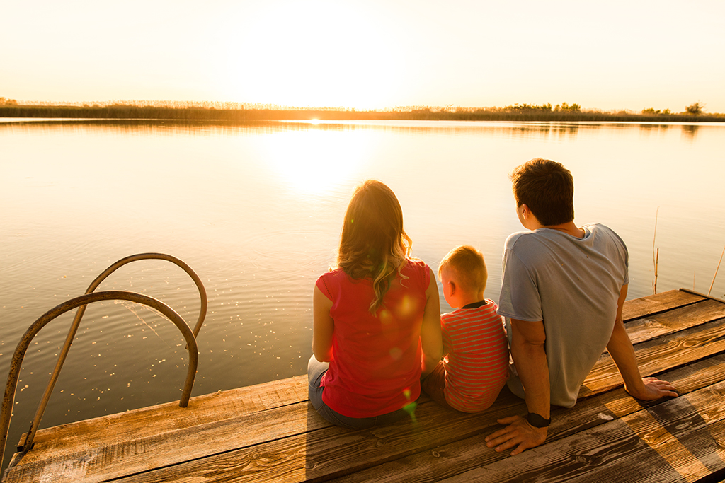 Family watching sunset on dock